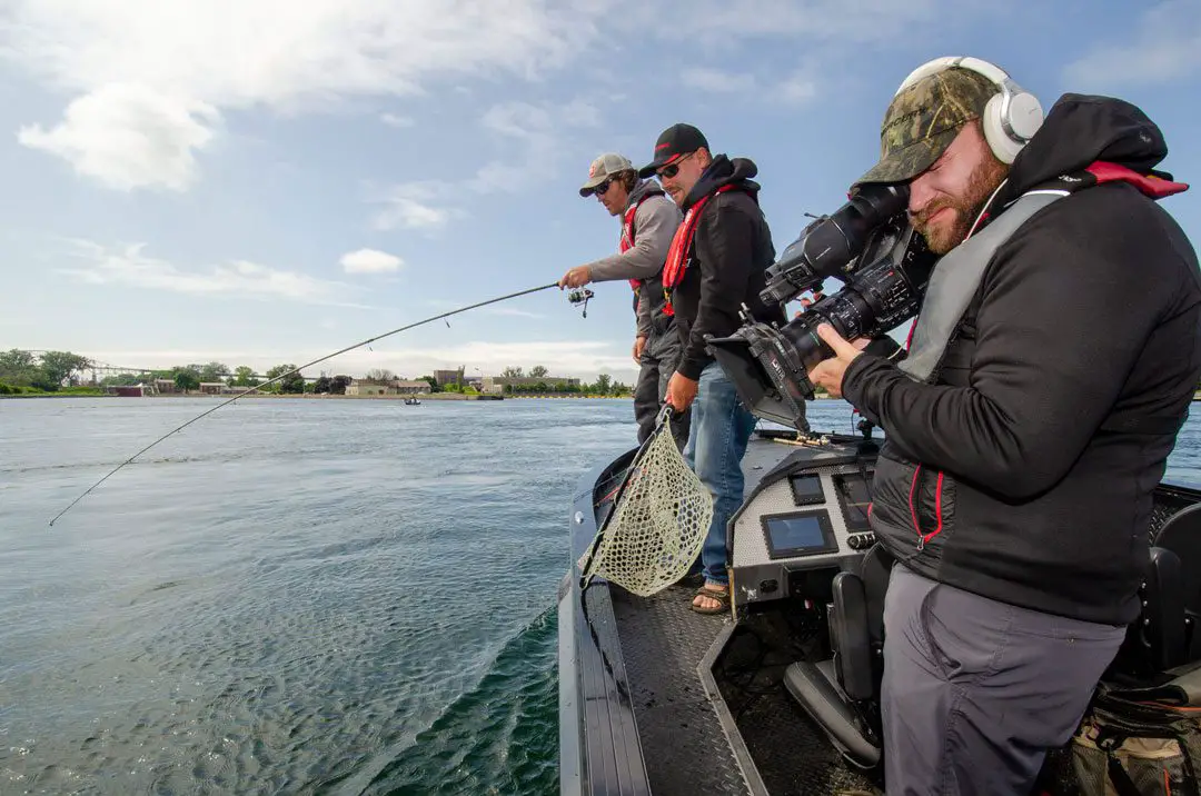 A cameraman captures Tyler landing an Atlantic Salmon