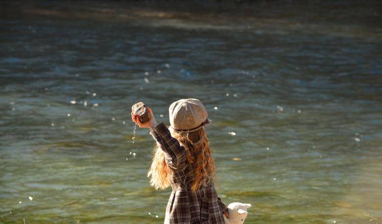 A child throwing a rock in a lake